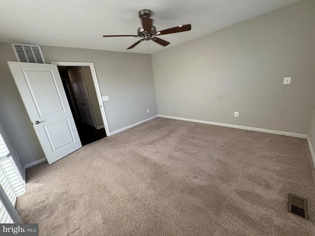 an empty room with windows and ceiling fan