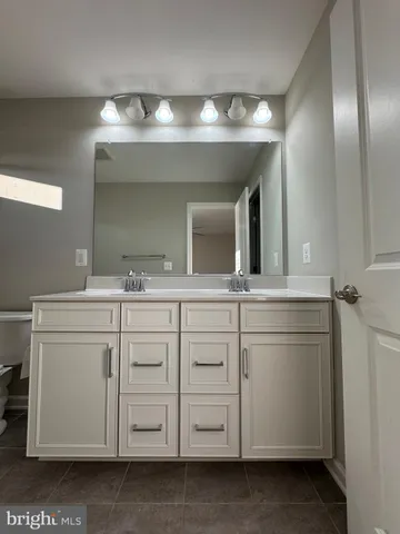 a spacious bathroom with a double vanity sink a toilet a mirror and shower