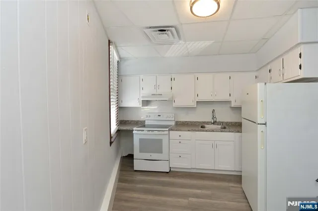 a kitchen with stainless steel appliances granite countertop a sink a stove a refrigerator and white cabinets