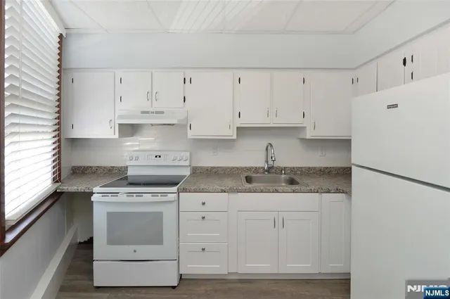 a kitchen with granite countertop white cabinets and white appliances