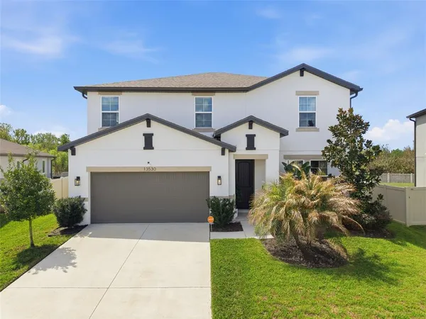 a view of a white house next to a yard with potted plants