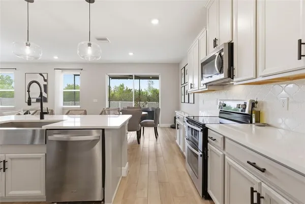 a kitchen with stainless steel appliances a table chairs refrigerator and cabinets