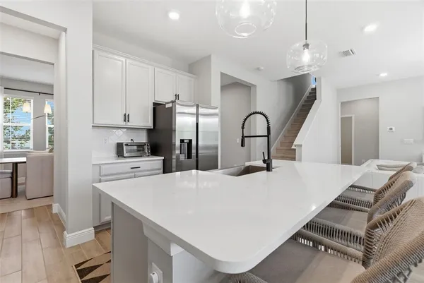 a kitchen with stainless steel appliances granite countertop a refrigerator a stove a sink dishwasher a dining table and chairs with wooden floor