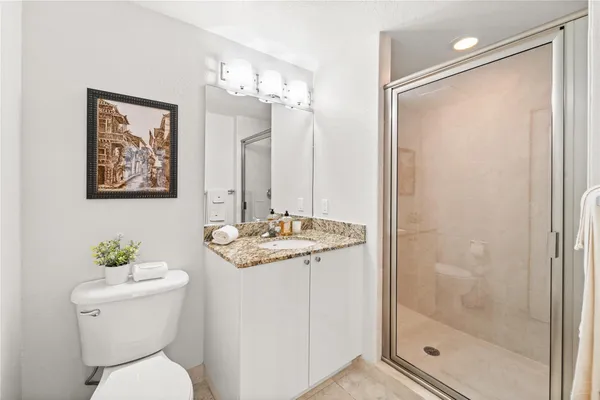 a bathroom with a granite countertop sink a toilet and shower