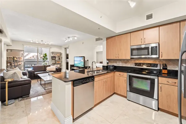 a kitchen with stainless steel appliances granite countertop a stove top oven a sink dishwasher a dining table and chairs with wooden floor