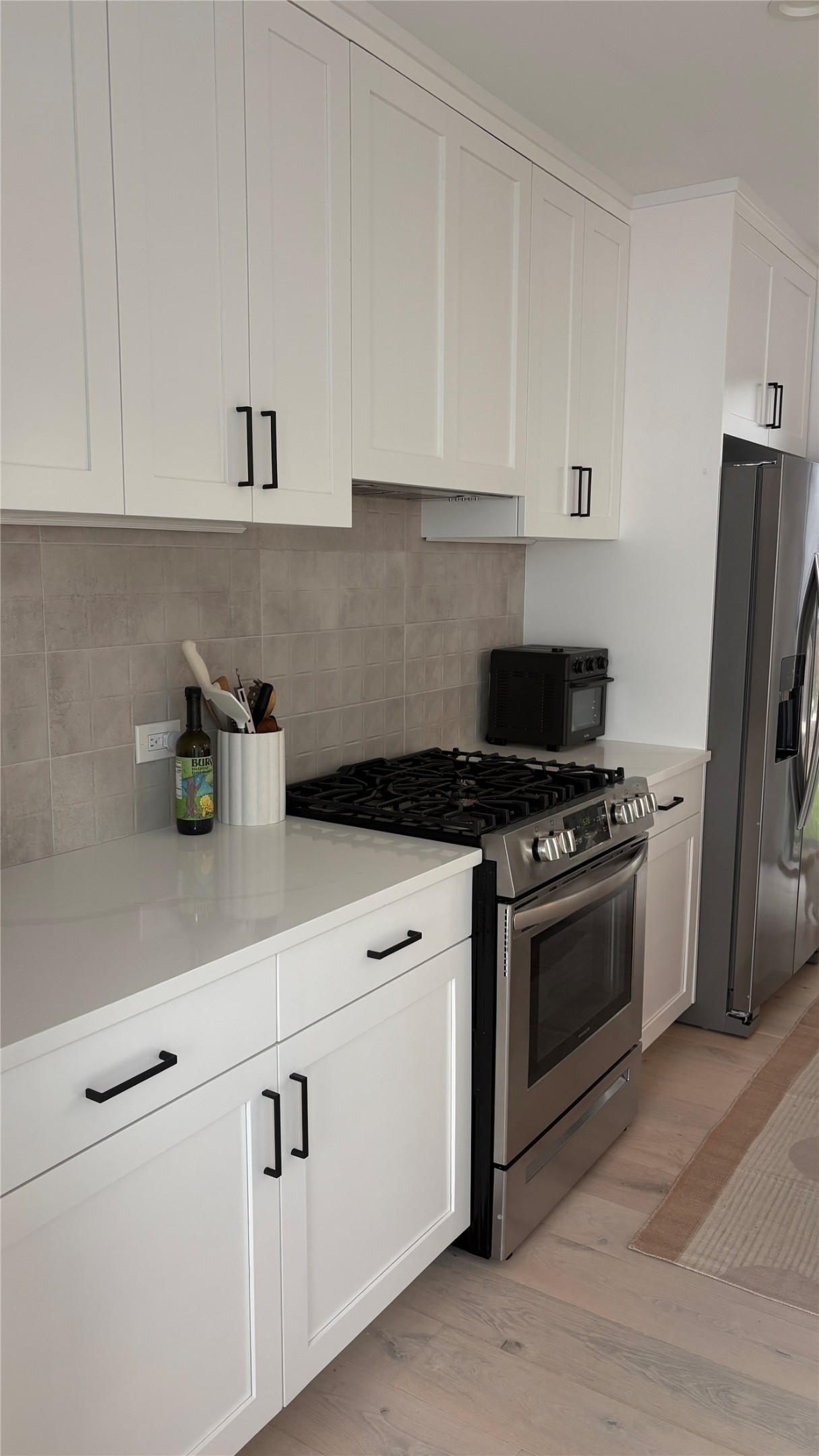 1816 Adina Street, Unit 2 Austin, TX 78721 - Photo 10 of 25 Modern kitchen featuring white shaker-style cabinetry with matte black hardware, light-toned countertops, and a gray subway tile backsplash