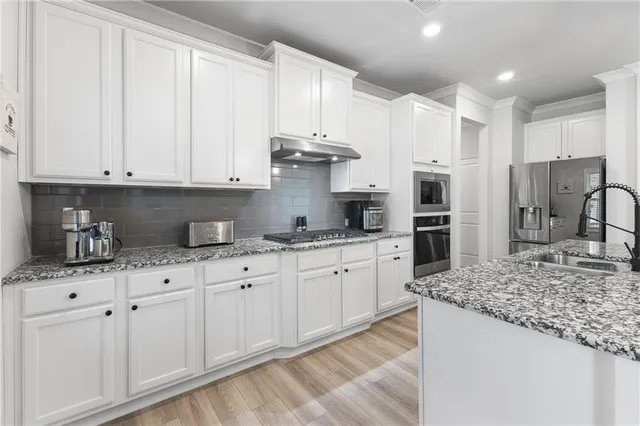 a kitchen with stainless steel appliances granite countertop a sink a stove and a refrigerator