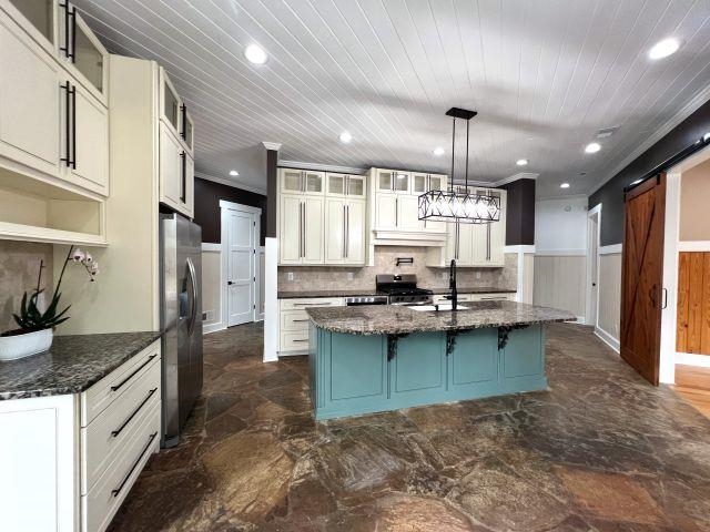 9490 Highway 196 Collierville, TN 38017 - Photo 9 of 40 Kitchen featuring glass insert cabinets, dark stone countertops, wainscoting, a kitchen island with sink, and stainless steel appliances
