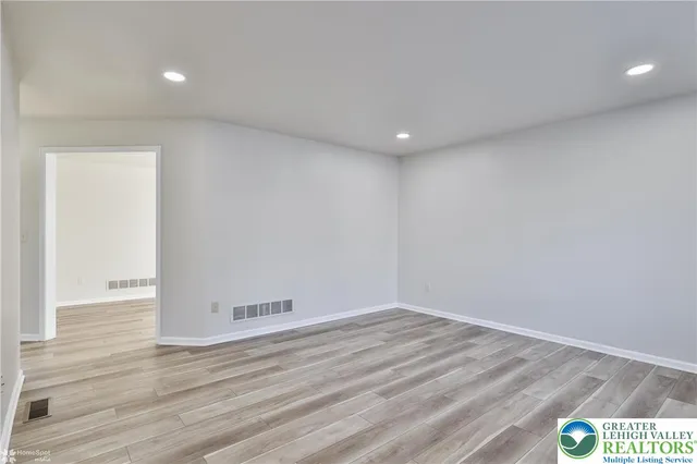 a view of a hallway with wooden floor and a kitchen
