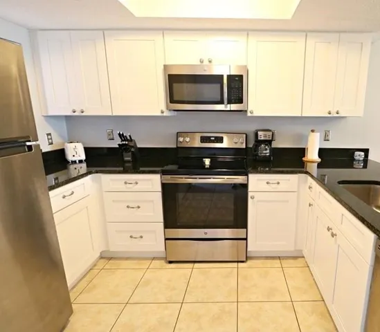 a kitchen with granite countertop a stove top oven microwave and cabinets