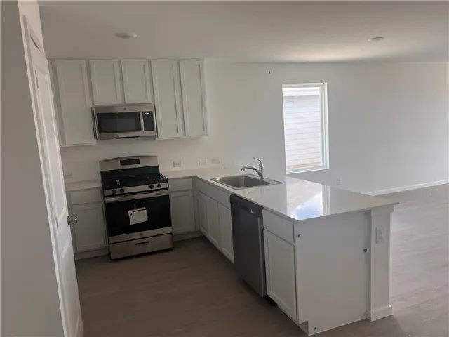 a kitchen with stainless steel appliances a stove microwave and sink