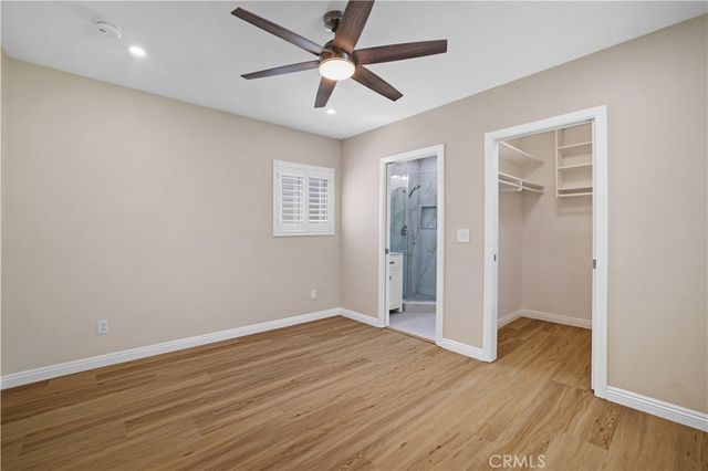 an empty room with wooden floor and a ceiling fan