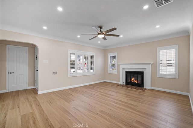 a view of an empty room with wooden floor fireplace and a window