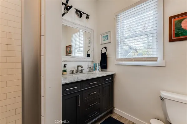 a bathroom with a granite countertop sink a toilet and a window