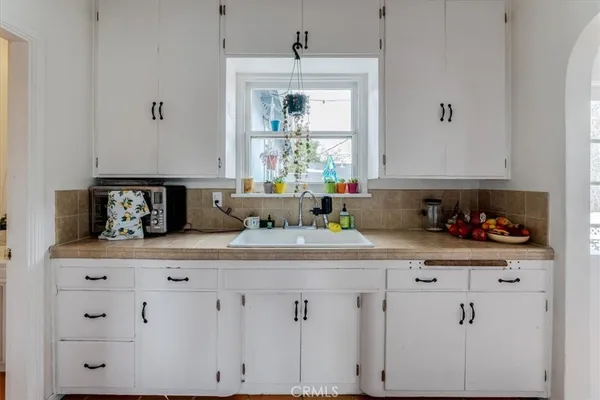 a kitchen with white cabinets and window