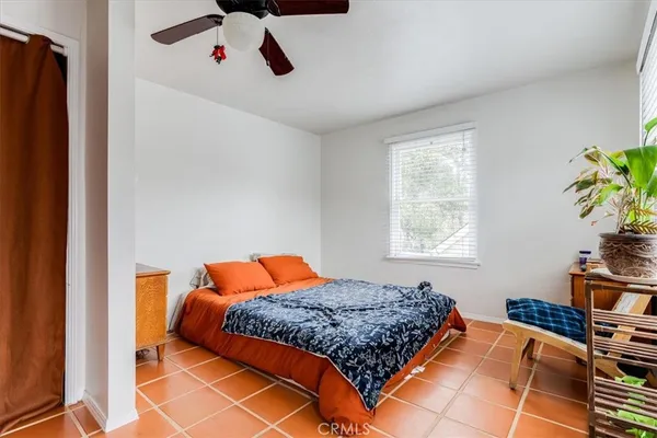 a bedroom with a bed and a potted plant on the dresser