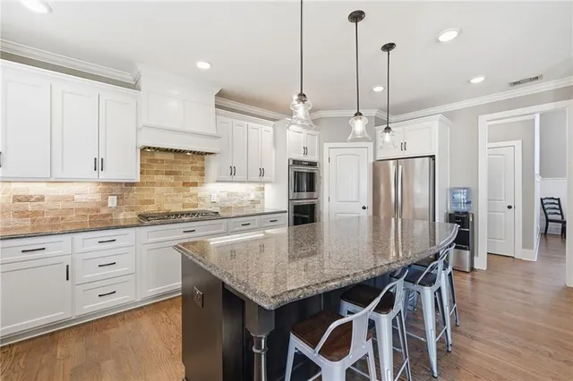 a kitchen with stainless steel appliances granite countertop a kitchen island and a refrigerator
