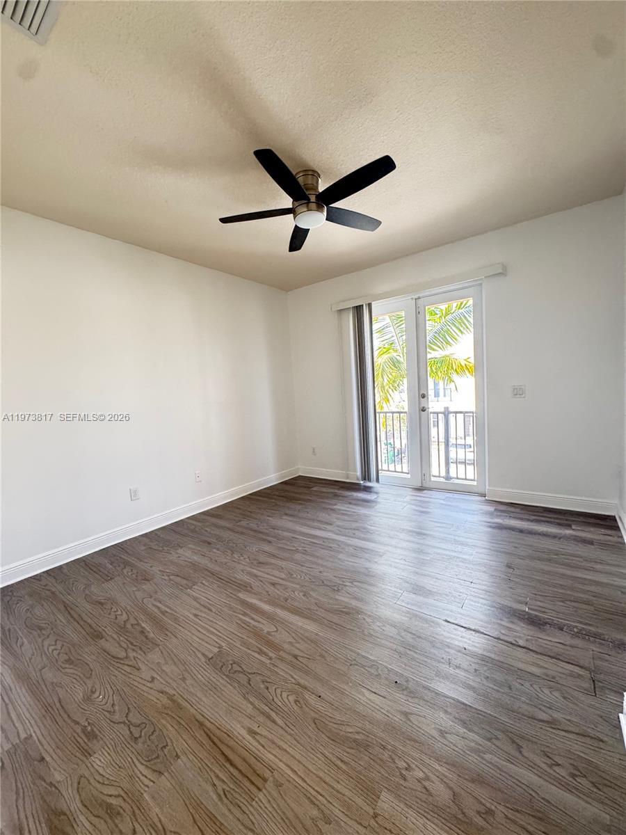 7658 Northwest 88th Terrace, Unit 12 Tamarac, FL 33321 - Photo 8 of 12 an empty room with wooden floor and windows