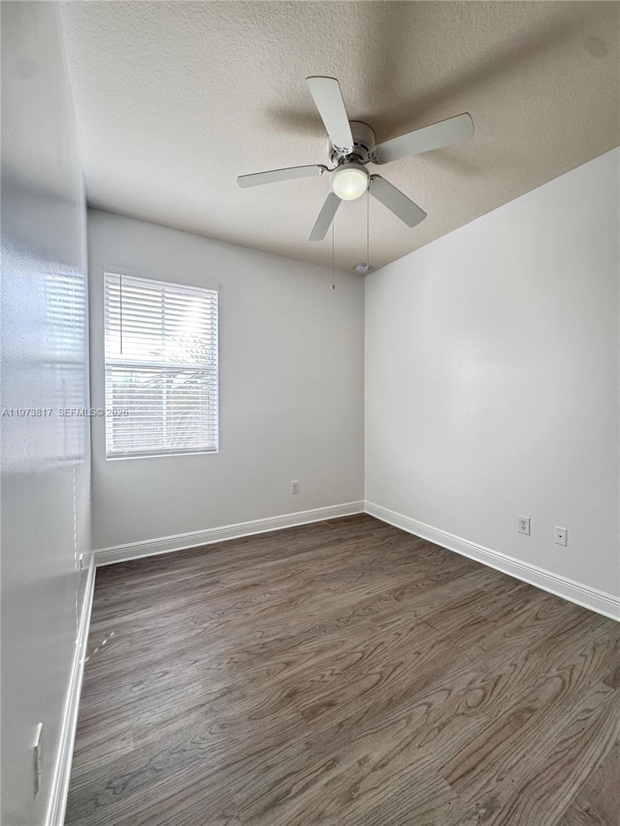 7658 Northwest 88th Terrace, Unit 12 Tamarac, FL 33321 - Photo 10 of 12 an empty room with wooden floor fan and windows