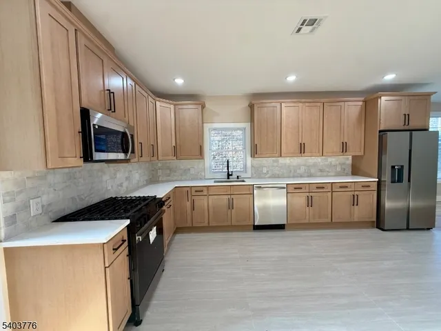 a kitchen with stainless steel appliances granite countertop a sink a stove and a microwave