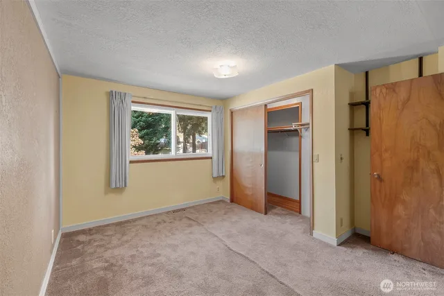 a view of an empty room with window and closet area