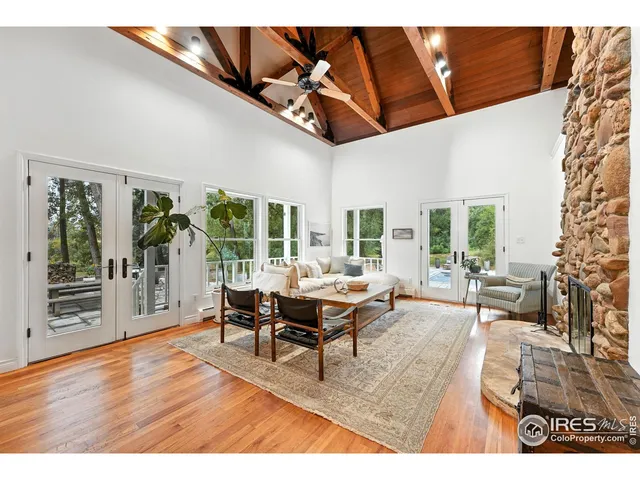 a living room with furniture a large window and wooden floor