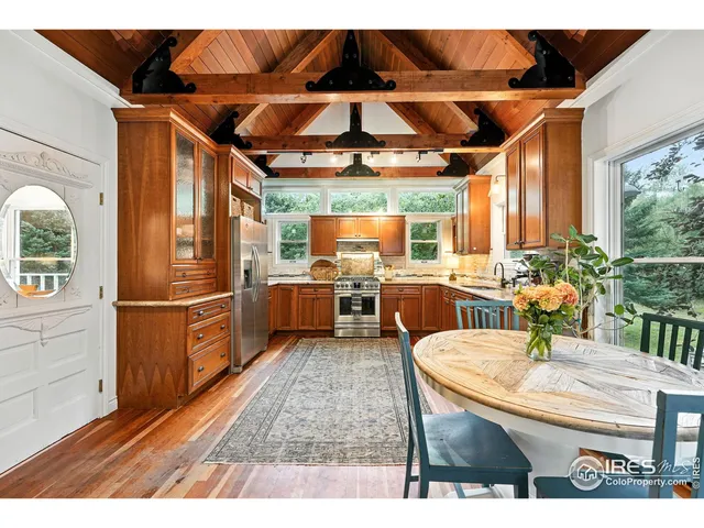 a kitchen with stainless steel appliances kitchen island granite countertop a table chairs and a refrigerator