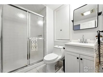a bathroom with a toilet a sink a glass door a shower and a mirror