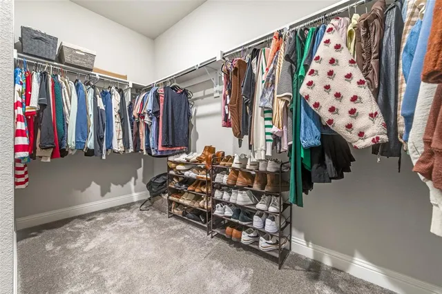 a view of walk in closet with clothes and shoes