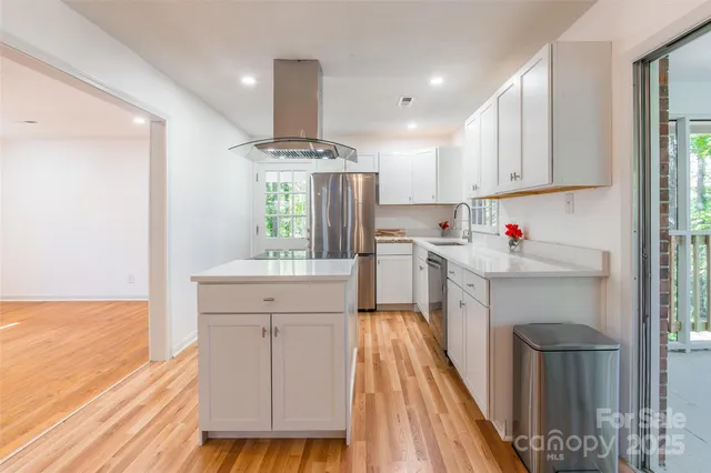 a kitchen with a sink appliances cabinets and wooden floor