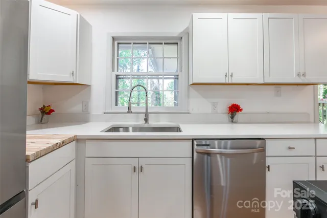 a kitchen with white cabinets and sink