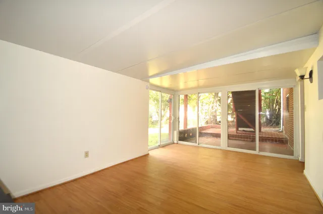 a view of a hallway with wooden floor and a large mirror