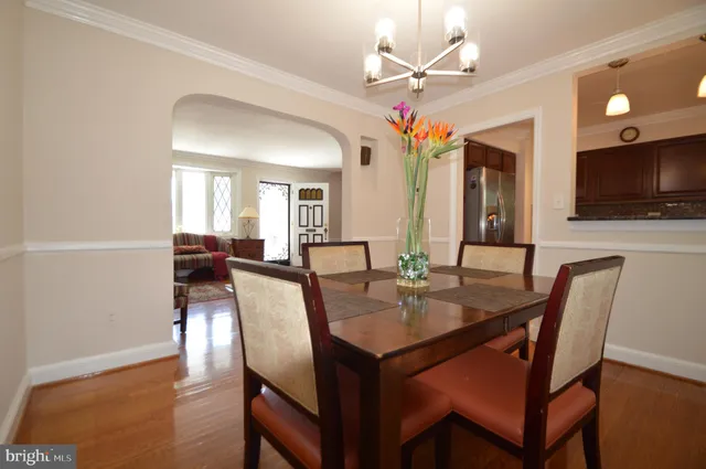an empty room with wooden floor and way to kitchen