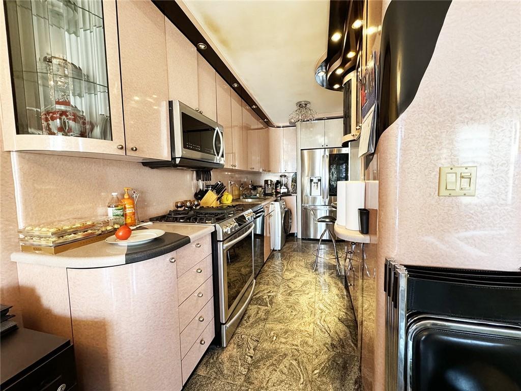 601 Surf Avenue, Unit 18E Brooklyn, NY 11224 - Photo 3 of 24 a kitchen with stainless steel appliances granite countertop a refrigerator a stove and a sink with wooden floor
