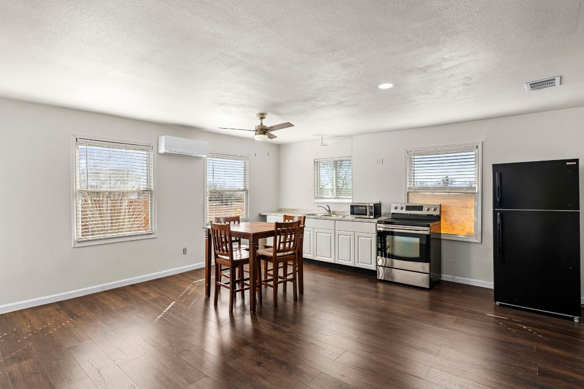 13415 Crane Road Buda, TX 78610 - Photo 16 of 22 Dining room with dark wood-style floors, a ceiling fan, a wall mounted air conditioner, and a textured ceiling