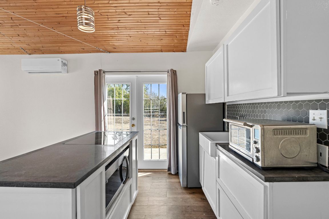 13415 Crane Road Buda, TX 78610 - Photo 6 of 22 Kitchen featuring wooden ceiling, white cabinets, stainless steel appliances, dark wood-type flooring, and decorative light fixtures