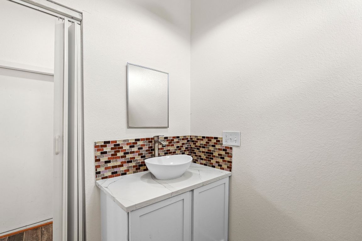 13415 Crane Road Buda, TX 78610 - Photo 10 of 22 Bathroom featuring vanity, tasteful backsplash, and a textured wall