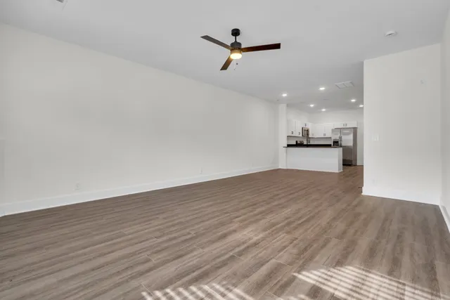an empty room with wooden floor ceiling fan and window