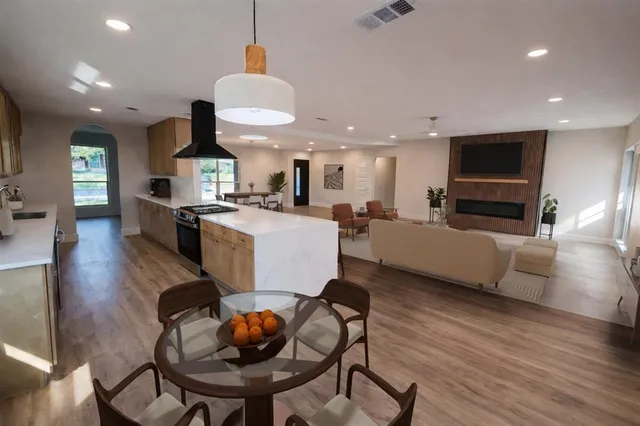 a living room with furniture kitchen view and a wooden floor