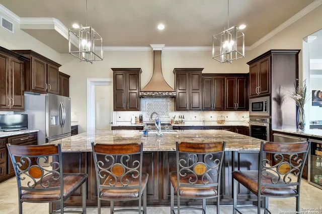 a kitchen with stainless steel appliances granite countertop a stove top oven a sink a dining table and chairs with wooden floor