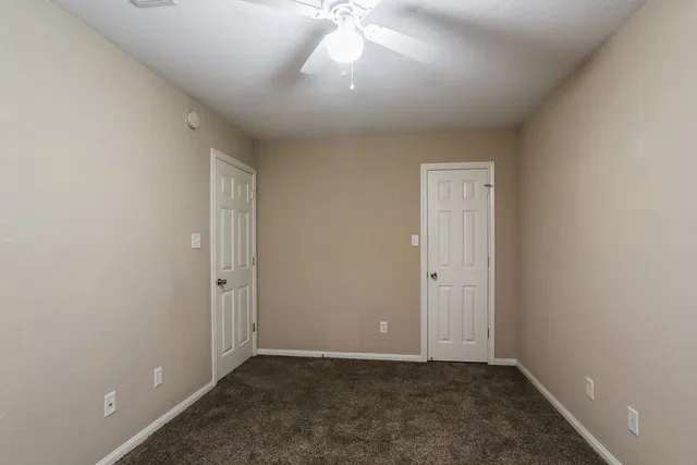 an empty room with a ceiling fan and window
