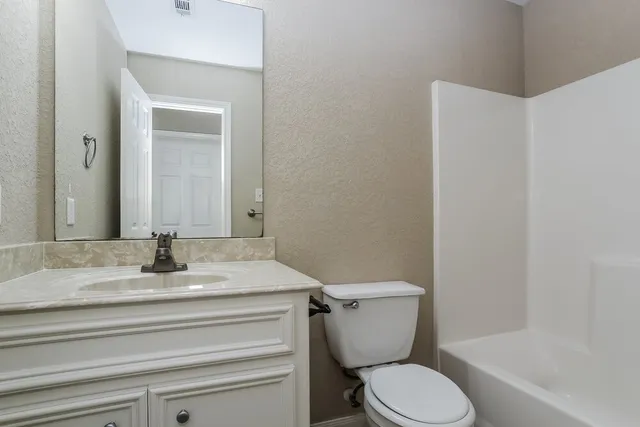 a bathroom with a granite countertop toilet and a sink