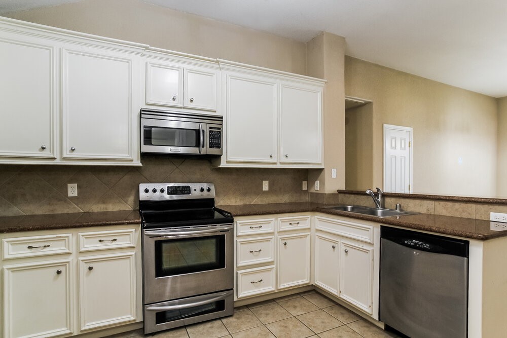131 Golfview Court Conroe, TX 77356 - Photo 7 of 16 a kitchen with granite countertop white cabinets and stainless steel appliances