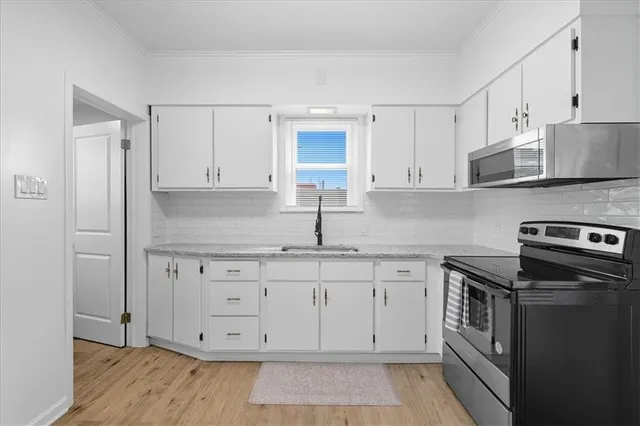 a kitchen with stainless steel appliances granite countertop a stove a sink and white cabinets