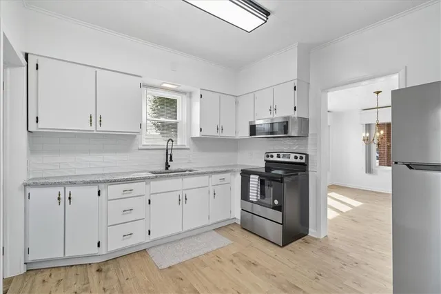 a kitchen with granite countertop white cabinets and stainless steel appliances
