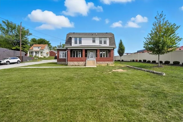 a view of a house with a big yard and large trees