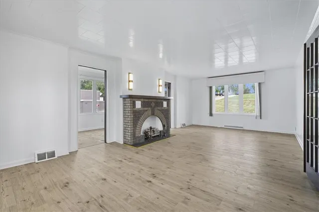 an empty room with windows and fireplace