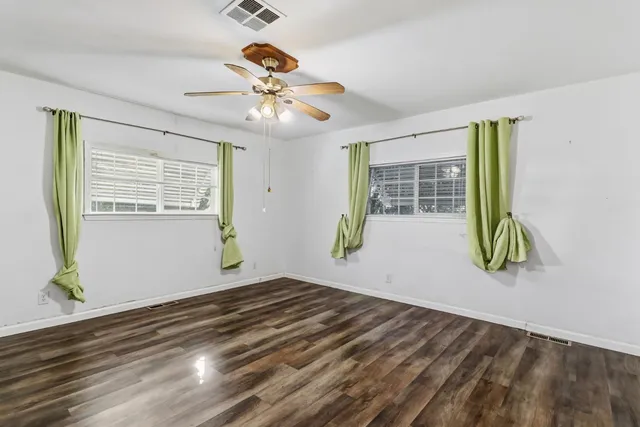 an empty room with wooden floor and windows