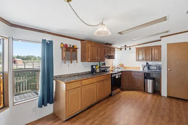 a kitchen with stainless steel appliances granite countertop a refrigerator a sink dishwasher a stove with wooden cabinets and floor