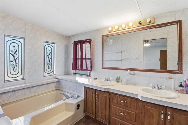 a bathroom with a tub a sink and mirror